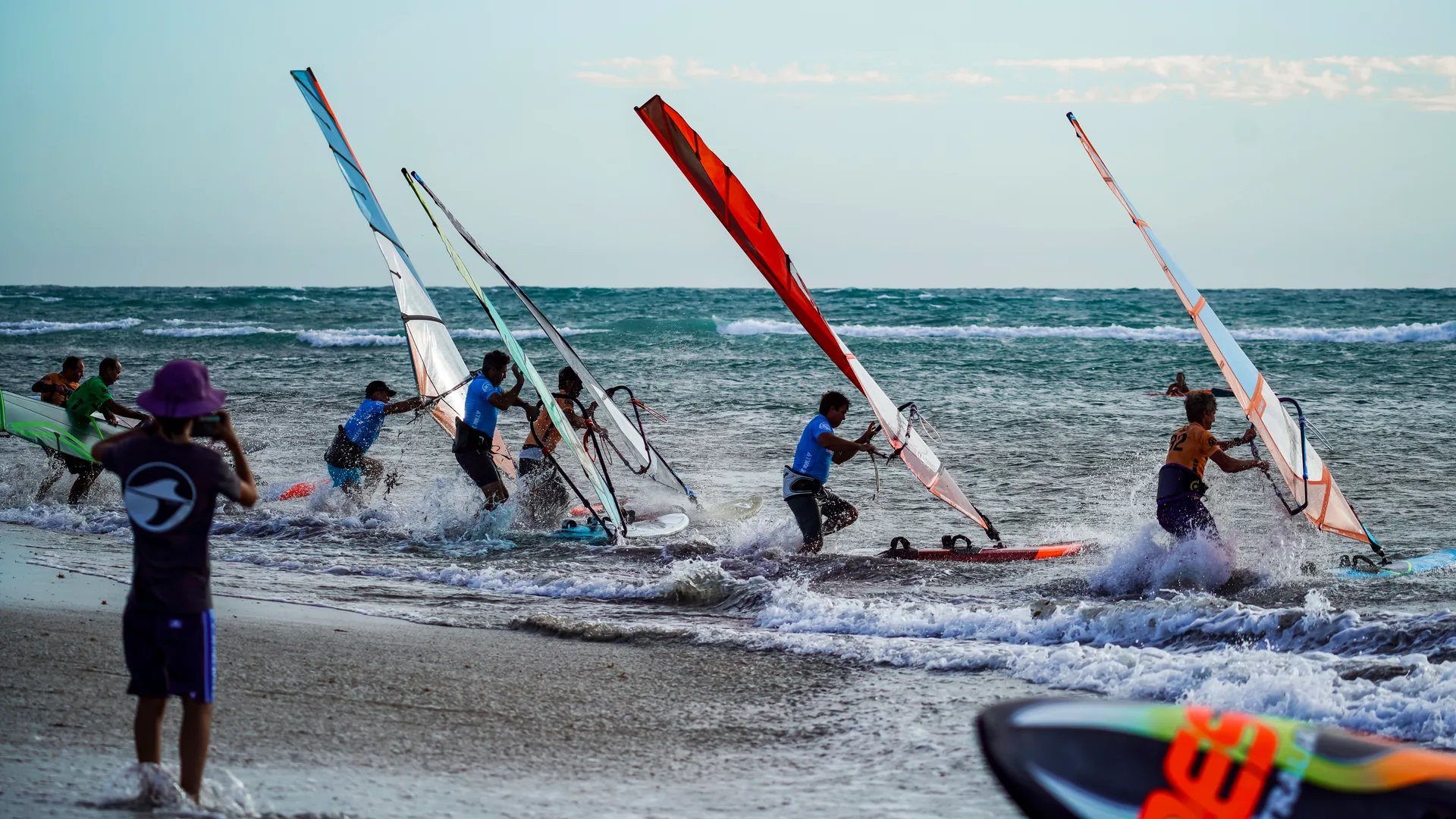 Windsurfers carrying their sails into the water for a Wave Rally beach start